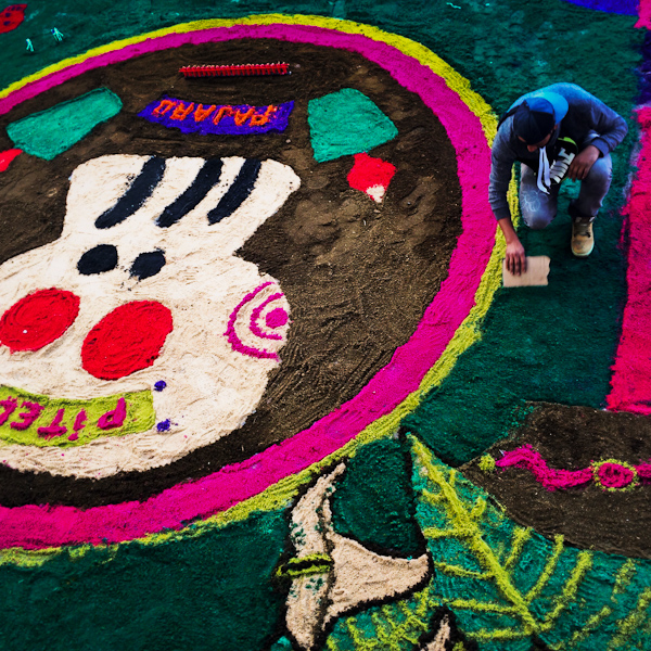 A Mexican boy creates a colorful sawdust carpet, displaying La Calavera icon, during the celebrations of the Day of the Dead (Día de Muertos) in Tláhuac, Mexico.