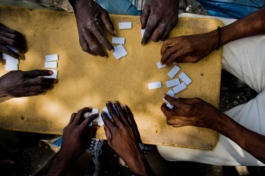 Haitian men play dominoes in the shadow of a tree during the hot afternoon in Port-au-Prince, Haiti.