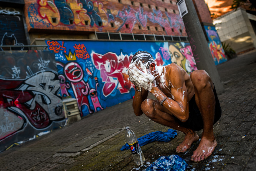 A Colombian drug consumer performs personal hygiene on the street in the center of Medellín, Colombia.