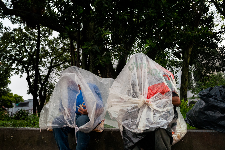 Colombian men smoke “bazuco” (a raw cocaine paste), hidden inside a large plastic bag in the streets of “El Bronx”, a drug distribution area in Medellín, Colombia.