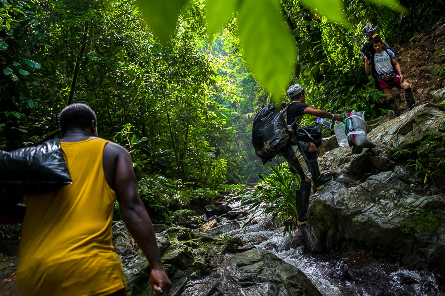 Migrants from Ecuador cross a stream while climbing a rocky trail in the wild and dangerous jungle of the Darién Gap between Colombia and Panamá.