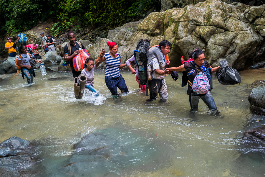 Migrants from Ecuador, Haiti and Nigeria wade through the river in the wild and dangerous jungle of the Darién Gap between Colombia and Panamá.