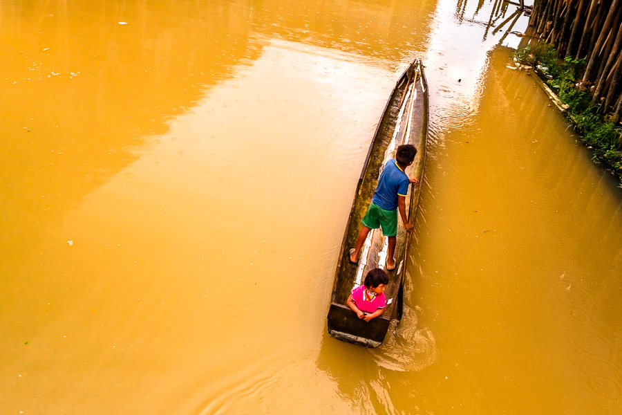 The indigenous children, belonging to the Emberá-Wounaan tribe, navigate a canoe on Río Atrato in Chocó, Colombia.