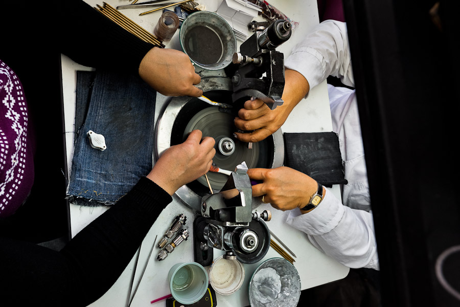 Emerald cutters polish gemstones on a faceting machine in a cutting and polishing workshop in Bogota, Colombia.