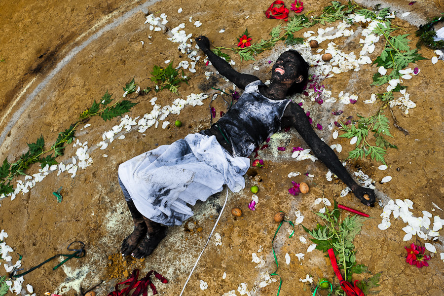 Diana R., who claims to be possessed by spirits, lies on the ground surrounded by flowers after a ritual of exorcism performed by Hermes Cifuentes in La Cumbre, Colombia.