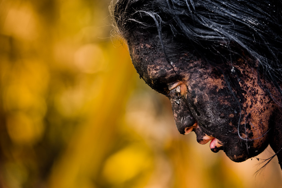 Diana R., who claims to be possessed by spirits, remains covered by black mud after a ritual of exorcism performed by Hermes Cifuentes in La Cumbre, Colombia.