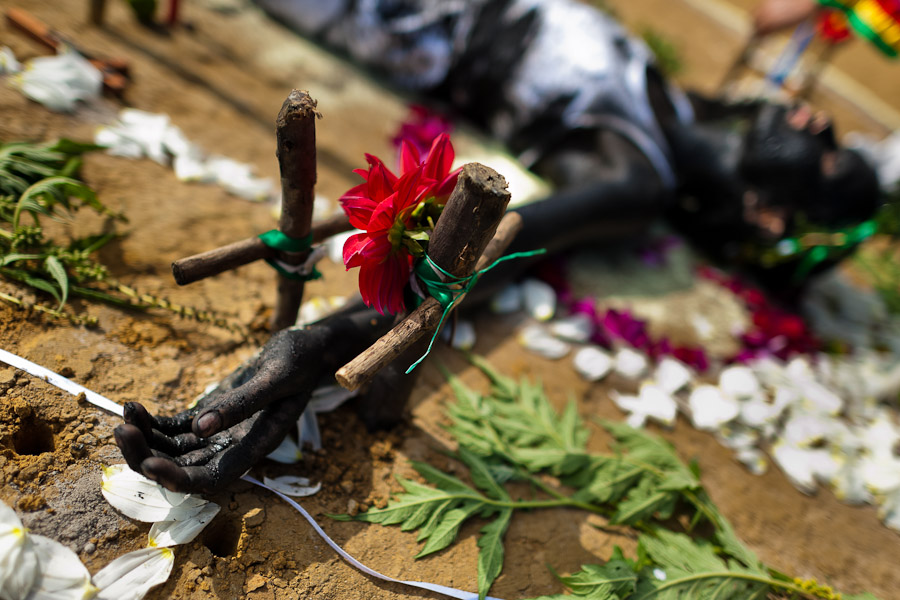 Diana R., who claims to be possessed by spirits, lies on the ground surrounded by crosses and flowers during a ritual of exorcism performed by Hermes Cifuentes in La Cumbre, Colombia.