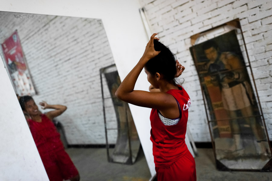 A young Colombian boxer ties hair into a ponytail before a sparring session in the boxing gym in Cali, Colombia.