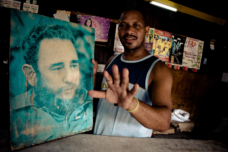 A Cuban shop assistant holds a large portrait photo of the Cuban Revolutionary leader Fidel Castro, in Havana.