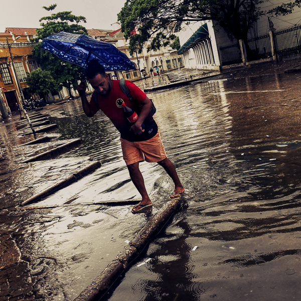 An Afro-Colombian man walks across the street flash flooded by torrential rain during the annual rainy season in Cartagena, Colombia.