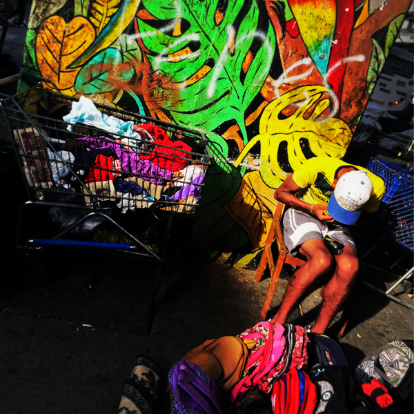 A young Colombian man sells worn clothes in a daily flea market underneath the elevated metro track in the center of Medellín, Colombia.