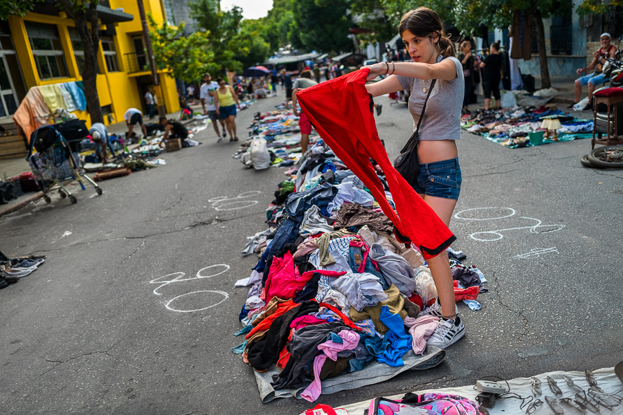 A young Uruguayan woman looks over a pair of pants from a pile of secondhand clothes during the Tristán Narvaja street market in Montevideo, Uruguay.