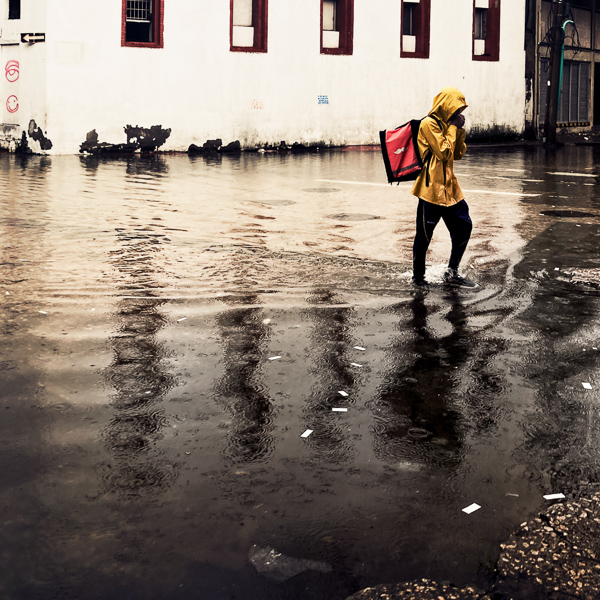 A Colombian food delivery courier crosses a street flash flooded by a heavy rain storm during the annual rainy season in Cartagena, Colombia.
