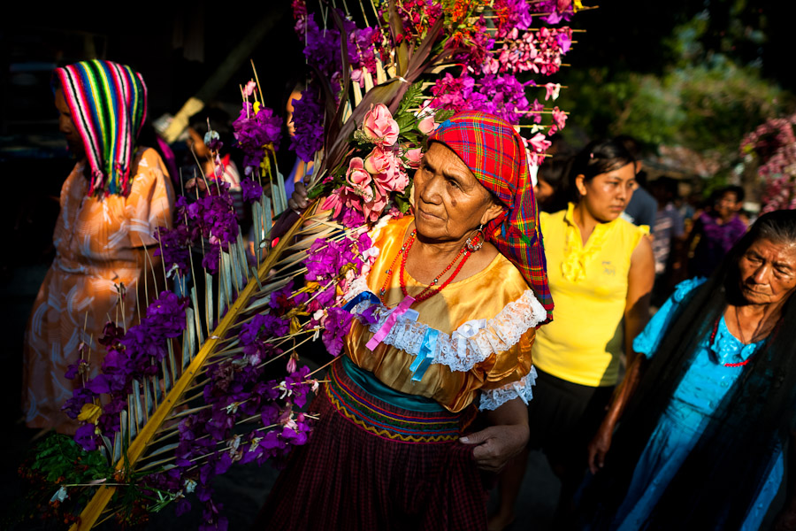 A Salvadoran woman carries a palm branch with colorful flower blooms during the procession of the Flower & Palm Festival in Panchimalco, El Salvador.
