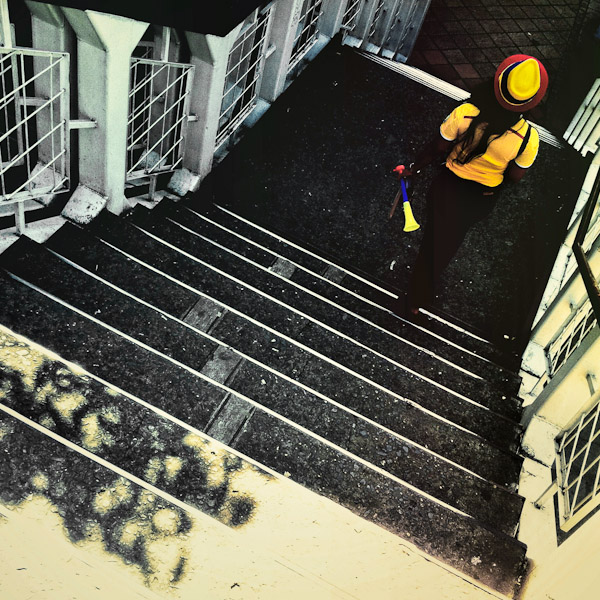 A Colombian girl, wearing the national football team t-shirt and holding a small trumpet, walks down the stairs in Cali, Colombia.