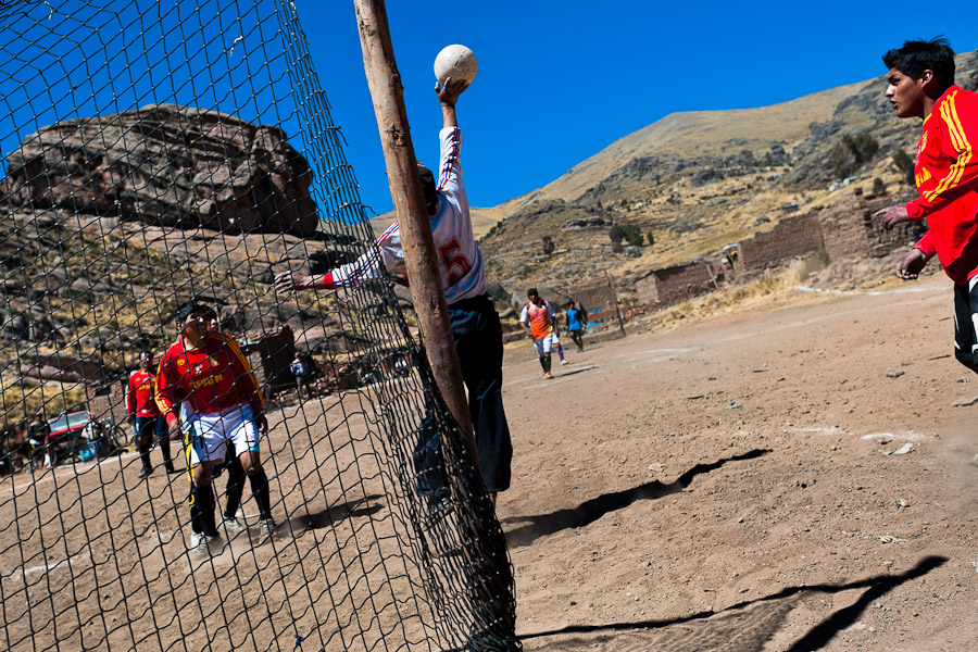 Indigenous men play football on a dirt field in the rural mountain community close to Puno, Peru.
