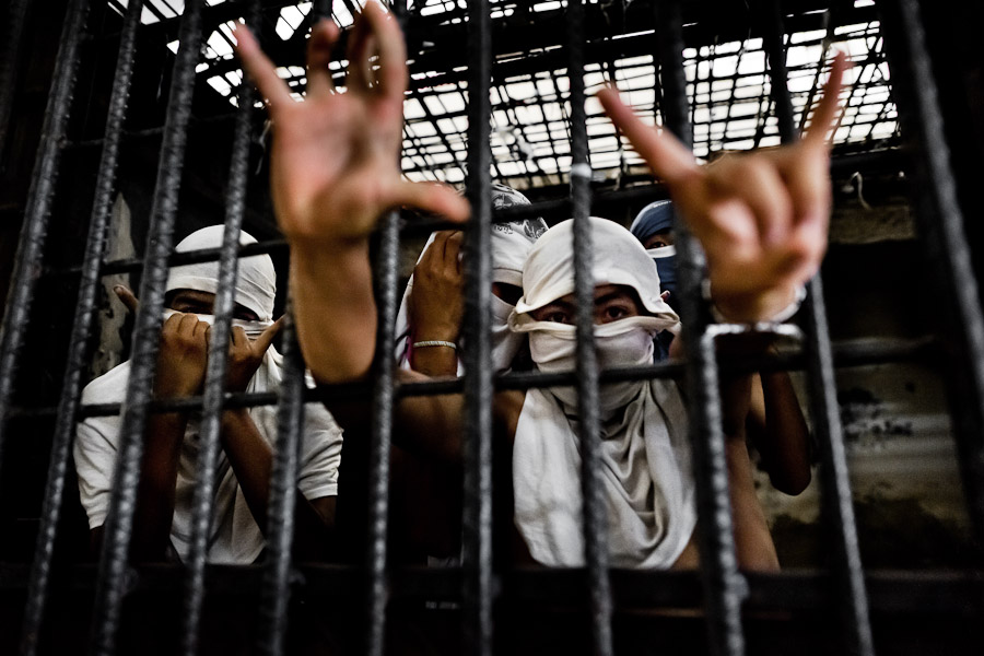 Members of the Mara Salvatrucha gang (MS-13) show hand signs, representing their gang, in a cell at the detention center in San Salvador, El Salvador.