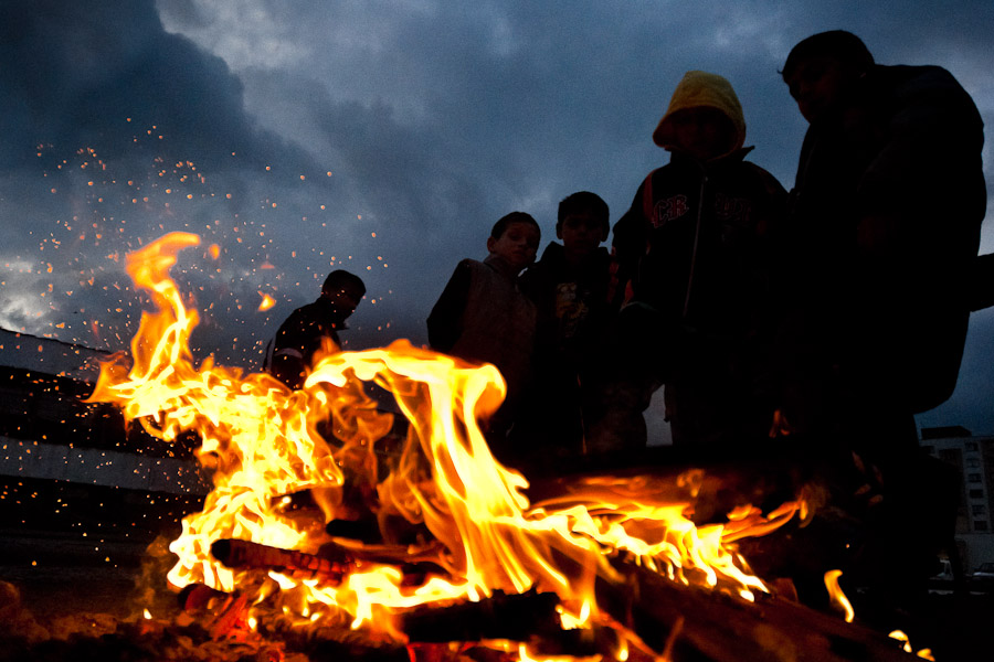 Young boys warm up by a fire on the street in the Gipsy ghetto of Chanov, Most, Czech Republic.