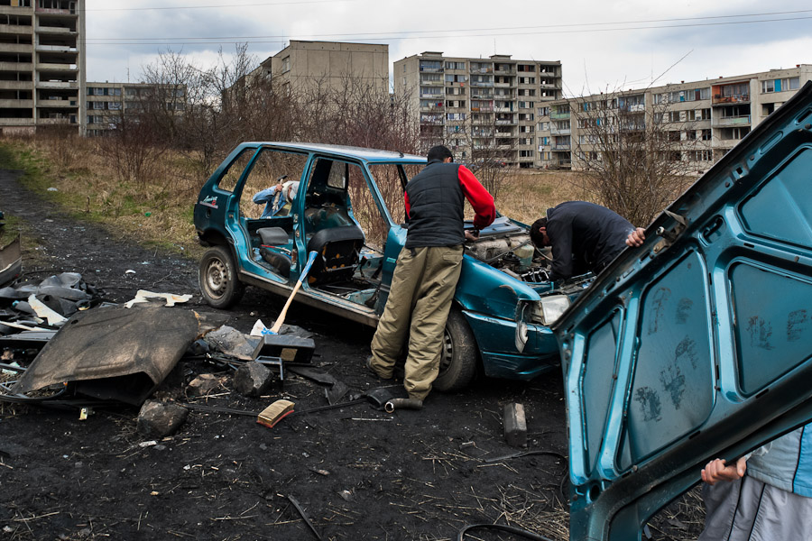 Gipsy men dismantle a used car to recycle metals in the Gipsy ghetto of Chanov on outskirts of Most.