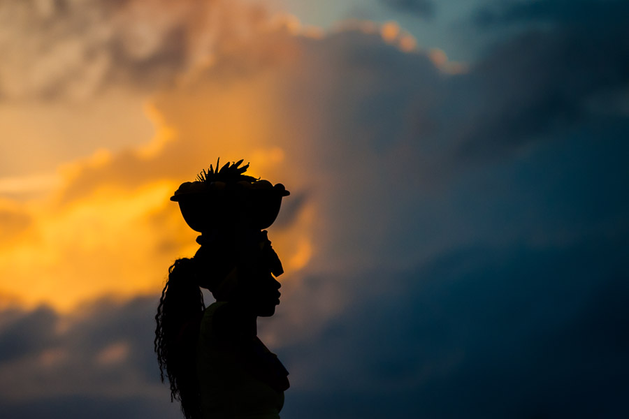 An Afro-Colombian girl, working as ‘palenquera’, carries a bowl full of fruits on her head during the sunset in Cartagena, Colombia.