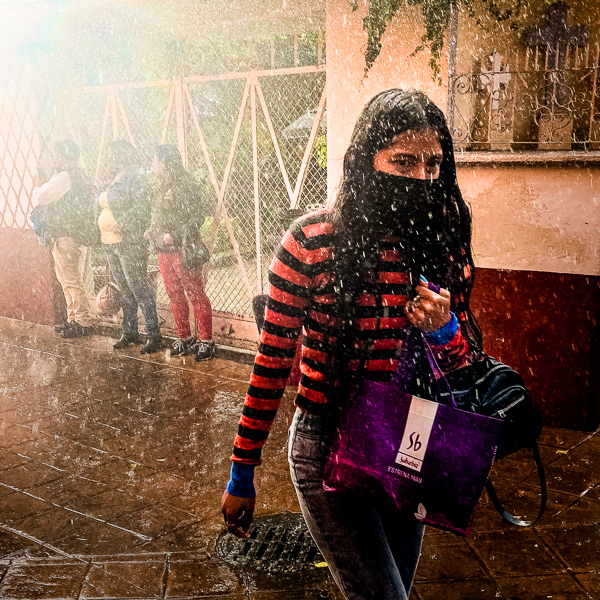 A Mexican girl walks in a tiny street during a sudden afternoon rain in Xochimilco, Mexico City, Mexico.