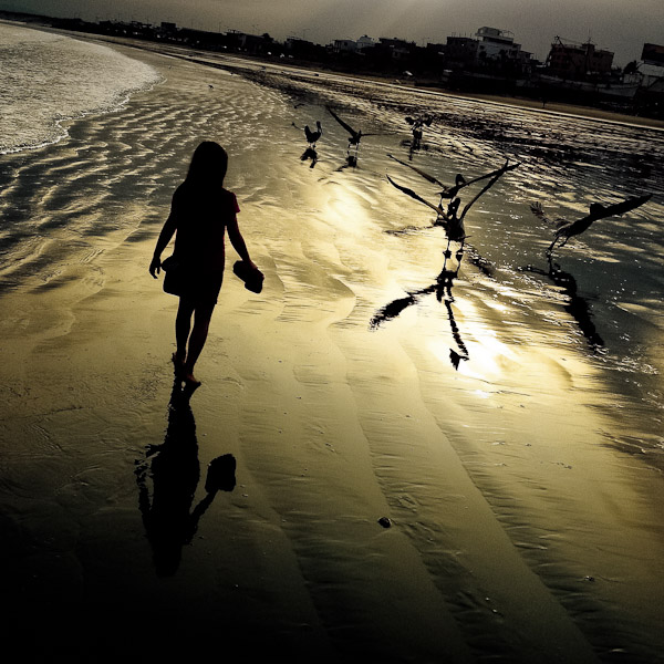 A girl walks on the low-tide beach at the sunrise in Manta, Ecuador.
