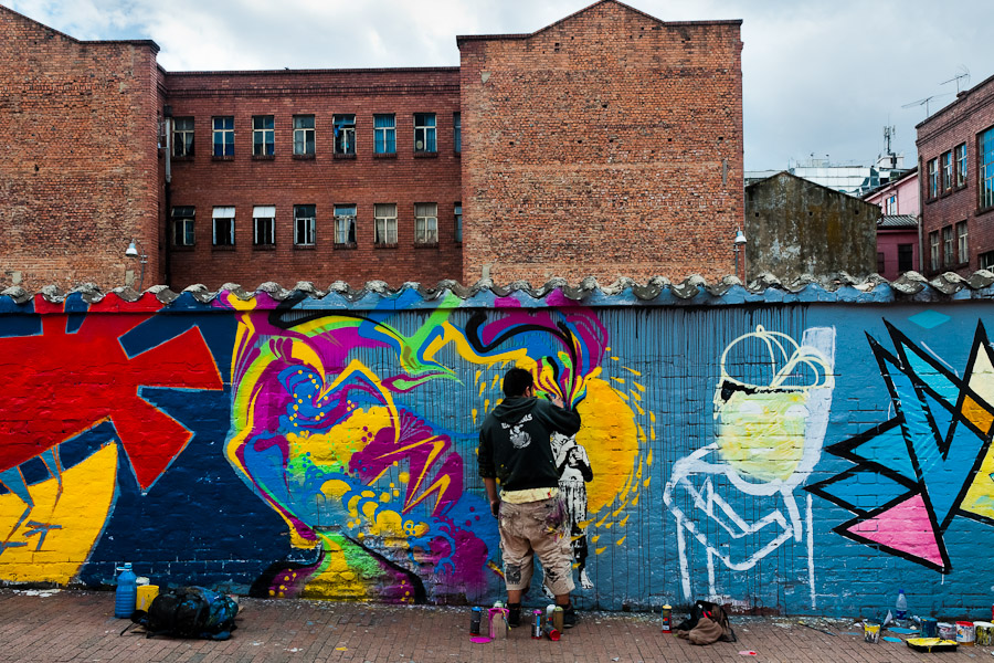 A Colombian graffiti artist named Stinkfish sprays graffiti on the wall in La Candelaria, Bogotá.