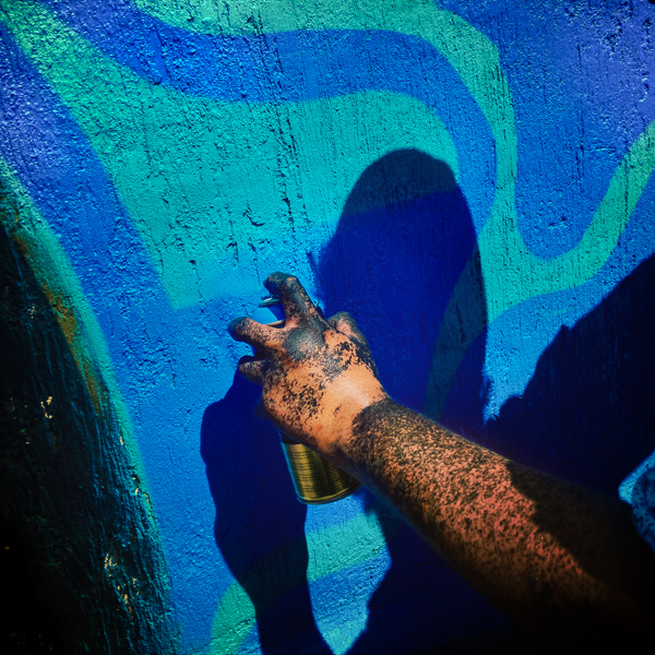 A hand of a Mexican street artist, splashed with black paint, is seen painting graffiti on the wall of a cemetery during a graffiti event in Guadalajara, Mexico.