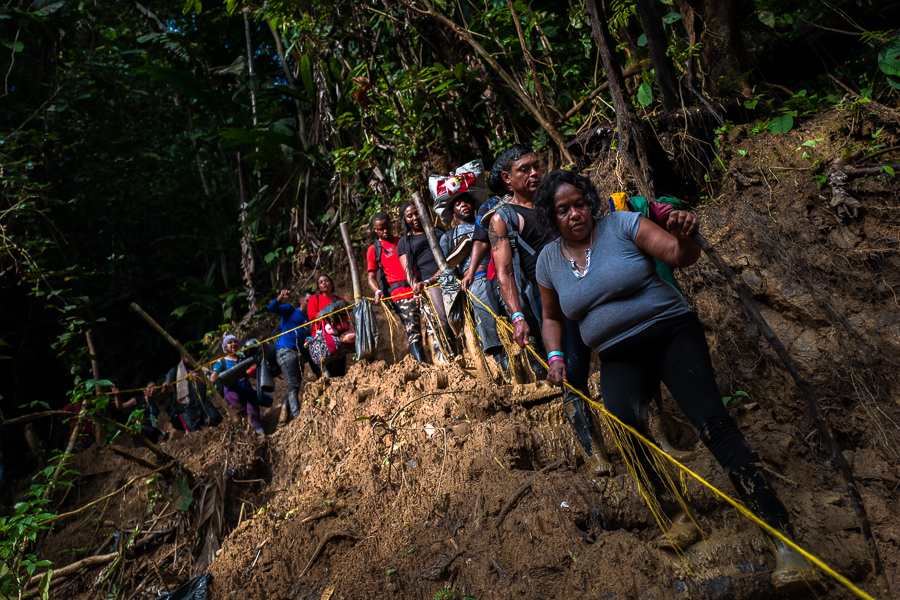 Haitian migrants climb down a muddy hillside trail in the wild and dangerous jungle of the Darién Gap between Colombia and Panamá.