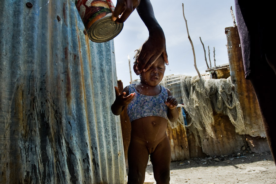 A Haitian woman washes her baby girl with wastewater in the slum of Cité Soleil, Port-au-Prince, Haiti.