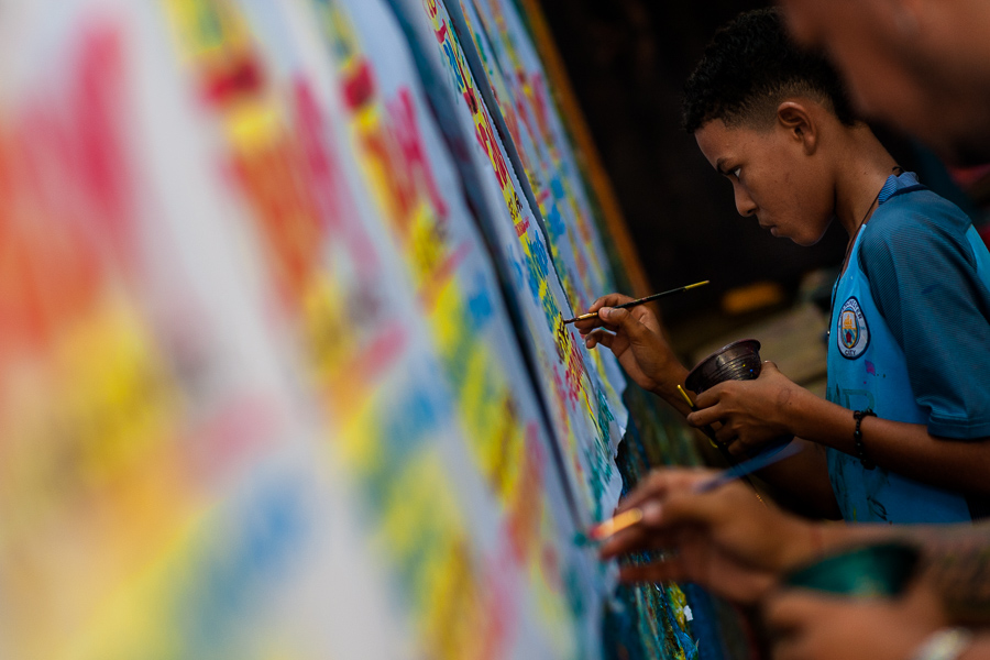 A Colombian sign painter apprentice writes with a brush while working on music party posters in the sign painting workshop in Cartagena, Colombia.