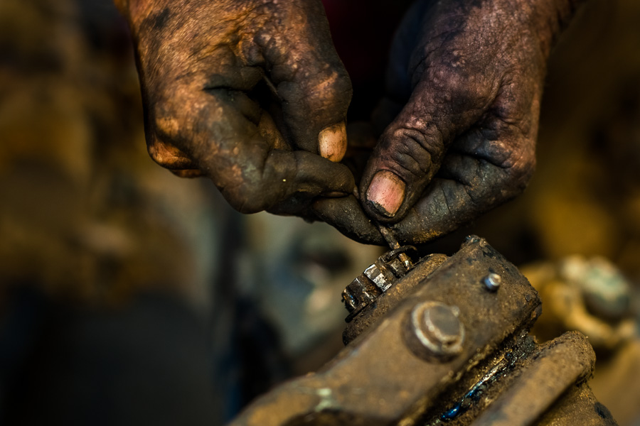 A Colombian mechanic works on an axle while performing maintenance on a truck in Barrio Triste, Medellín, Colombia.