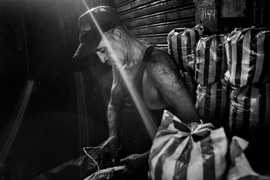 A Colombian charcoal worker fills plastic bags with charcoal in the street market in Barranquilla, Colombia.