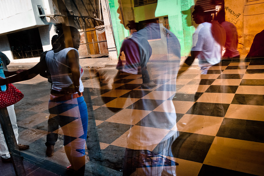 A reflection of Cubans, walking on the street, is seen in a shop window in Havana, Cuba.