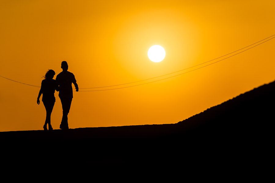 A tourist couple walk arm in arm on the stone walls, surrounding the colonial walled city, during the sunset in Cartagena, Colombia.