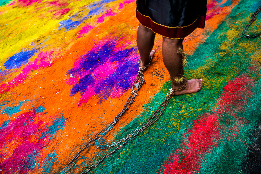 A chained Catholic devotee walks on a colorful sawdust carpet with the penitential procession held during the Holy week festivities in Atlixco, Mexico.