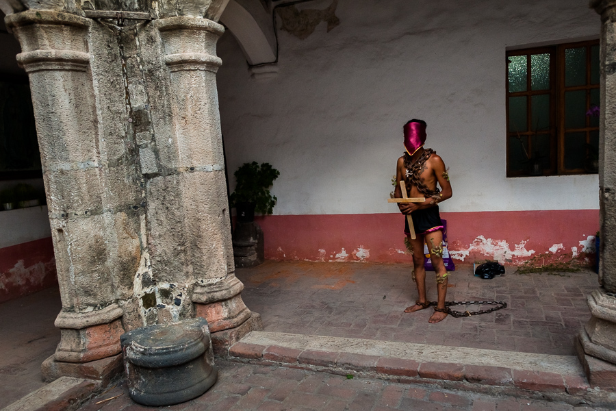 A chained Catholic penitent, holding a wooden cross, prepares to participate in the Holy week procession in Atlixco, Mexico.