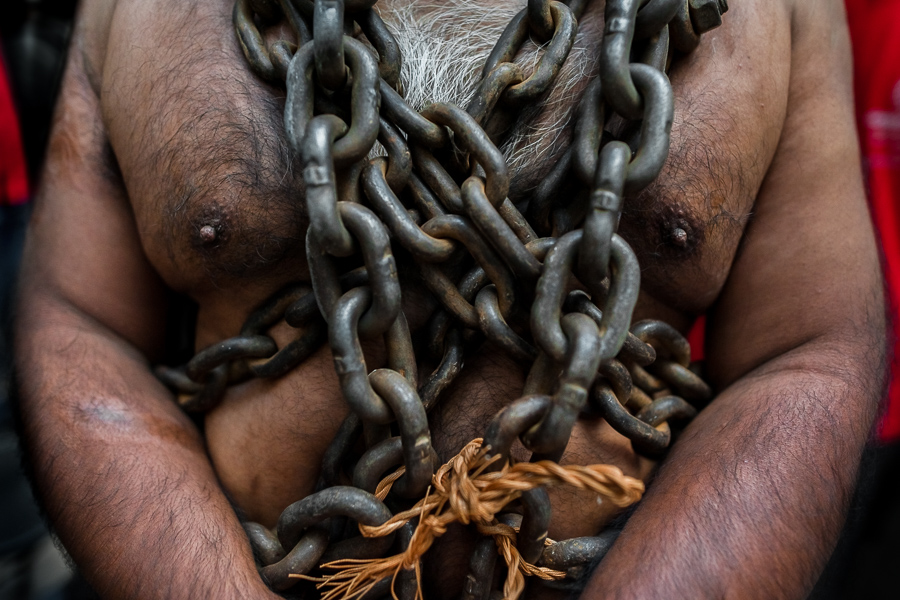 A Catholic penitent, wearing heavy chains on his shoulder, prepares to walk in the Holy week procession in Atlixco, Mexico.