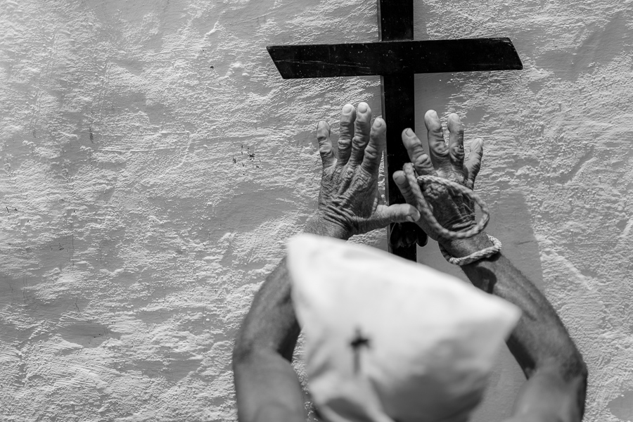 An Afro-Colombian man prays at a prayer station marked by a wooden cross during the Holy Week religious procession in Santo Tomás, Colombia.