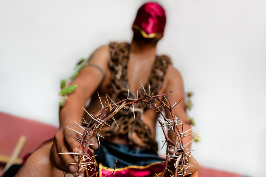 A hooded penitent, wearing chains and holding a crown of thorns, prepares to participate in the Holy week procession in Atlixco, Mexico.