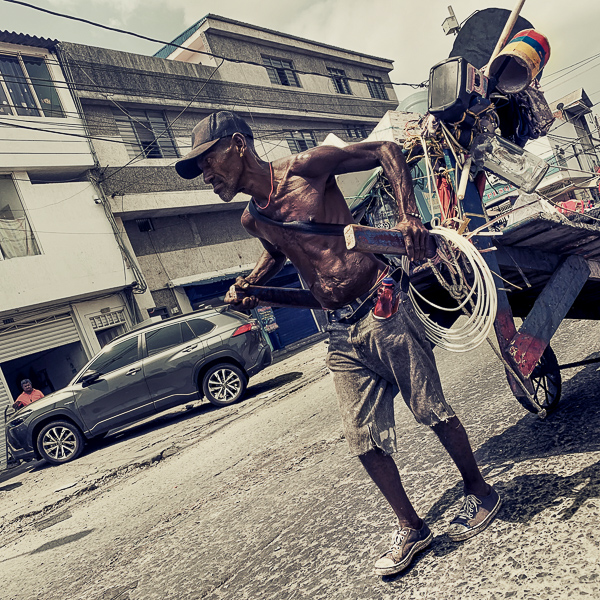 A homeless Afro-Colombian man pulls a cart loaded with garbage for recycling and discarded items in Cali, Colombia.