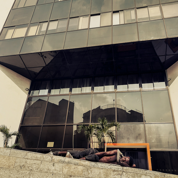 A homeless Afro-Colombian man sleeps in front of a bank in the center of Cali, Colombia.