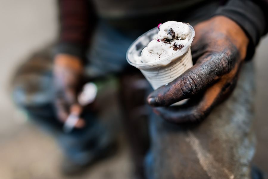 A Colombian mechanic holds a cup of ice cream during a short work break in Barrio Triste, Medellín, Colombia.