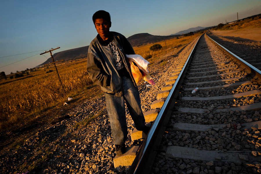 A Guatemalan immigrant waits on the railroad track to climb up the cargo train passing through the train station in Huehuetoca, Mexico.