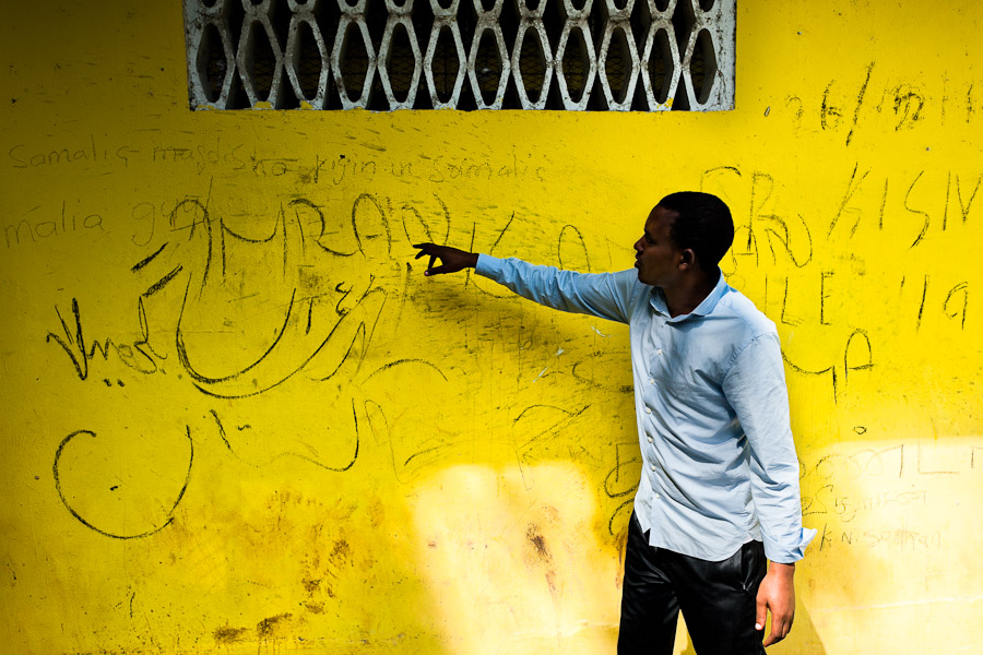 A young Somali immigrant, heading the southern U.S. border, translates the Arabic script writings on the wall of an immigrant detention center in Metetí, Panama.