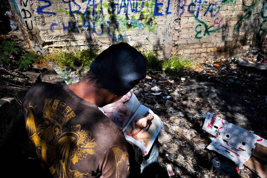 A Honduran immigrant browses through a US porn magazine while waiting near the railroad track to climb up the cargo train known as ‘La Bestia’ (The Beast) in Mexico City, Mexico.