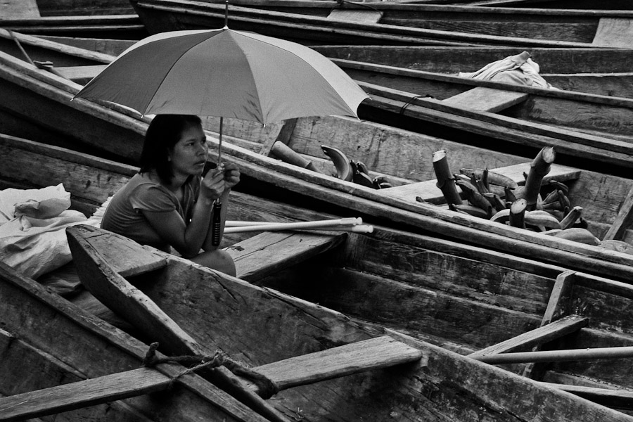 An Indian girl protecting herself with umbrella from the tropical weather in Amazonia.