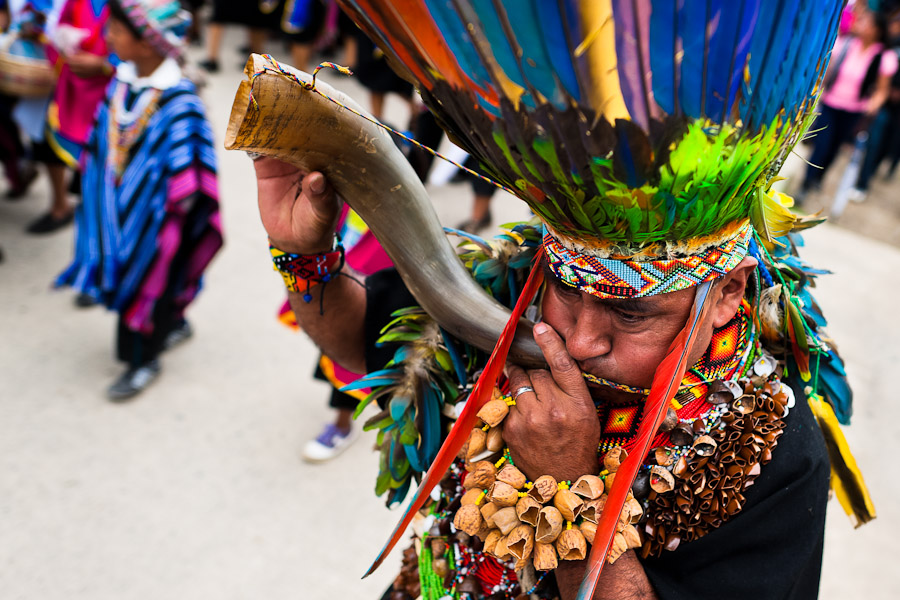 A shaman from the Kamentsá tribe, wearing a colorful feather headgear, plays horn trumpet during the Carnival of Forgiveness, a traditional indigenous celebration in Sibundoy, Colombia.