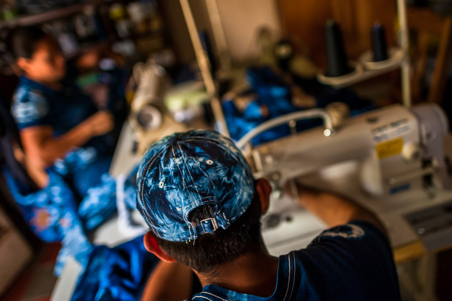 A Salvadoran seamster sews an indigo-dyed tote bag on the sewing machine in an artisanal clothing workshop in Santiago Nonualco, El Salvador.