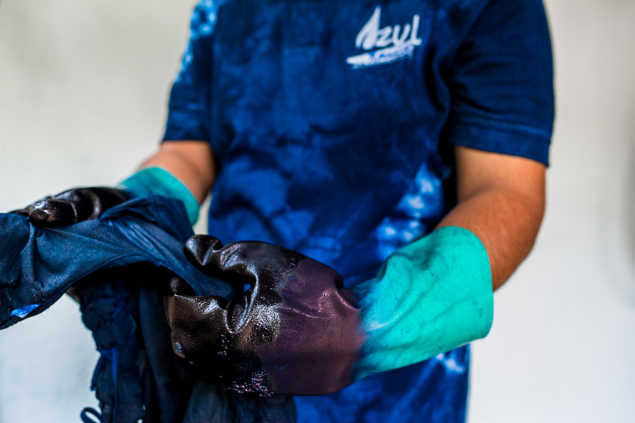 A Salvadoran textile dyer applies a natural indigo dye onto a wrapped cloth in an artisanal clothing workshop in Santiago Nonualco, El Salvador.
